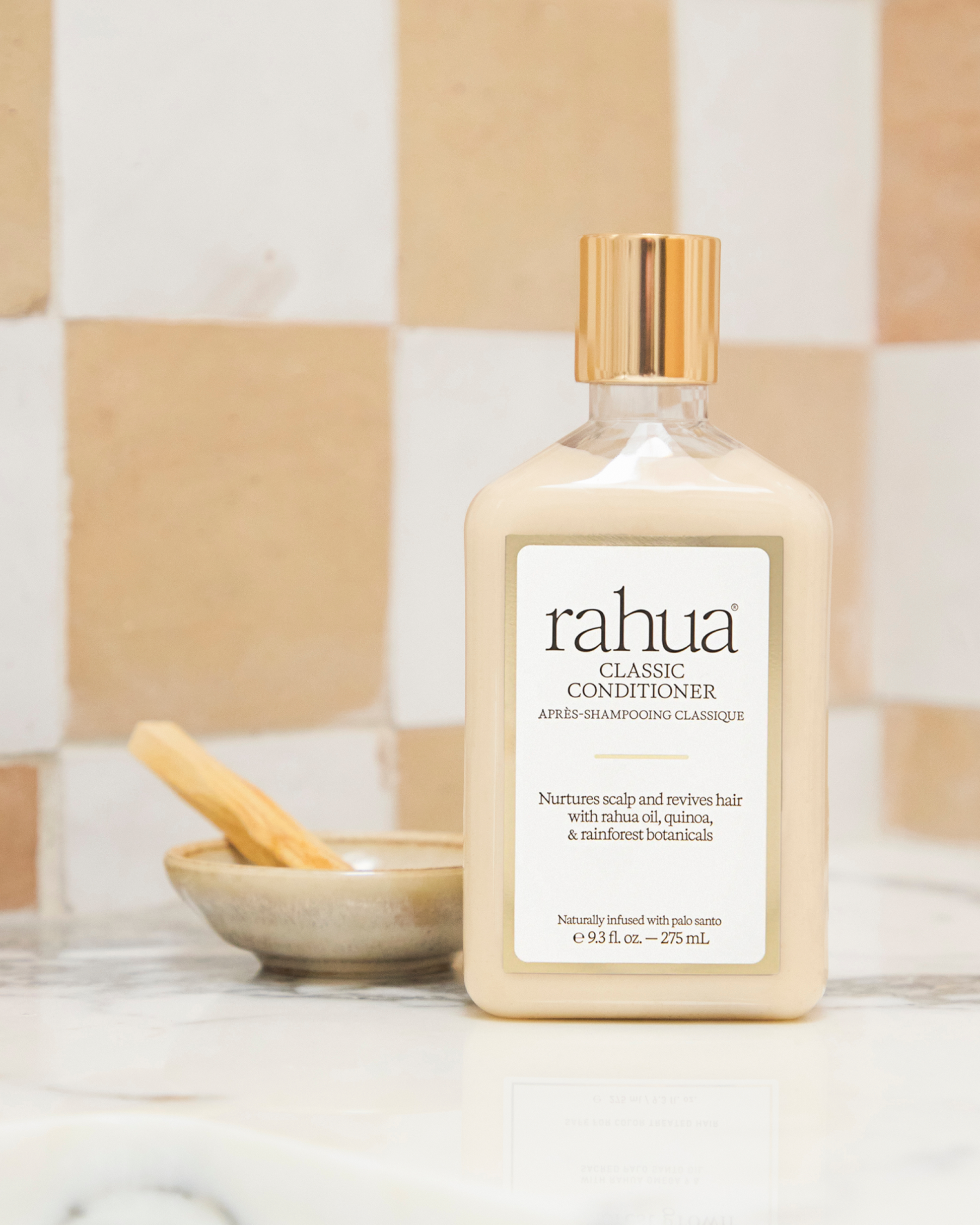 Bottle of rahua classic conditioner on a bathroom counter with a checkered tile background|variant:93-oz,18-oz