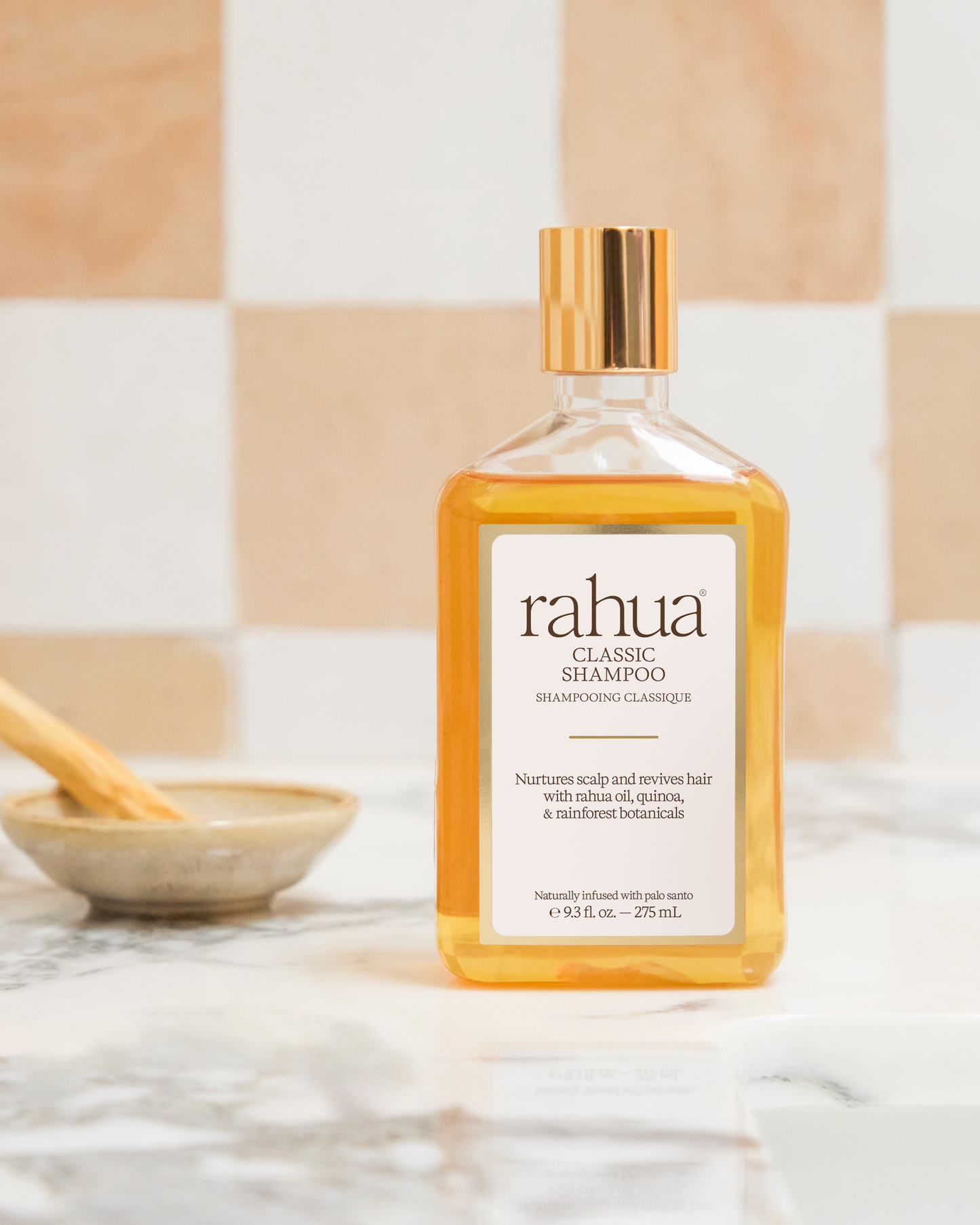 Rahua shampoo bottle on a marble surface with a neutral tile background|variant:93-oz,18-oz