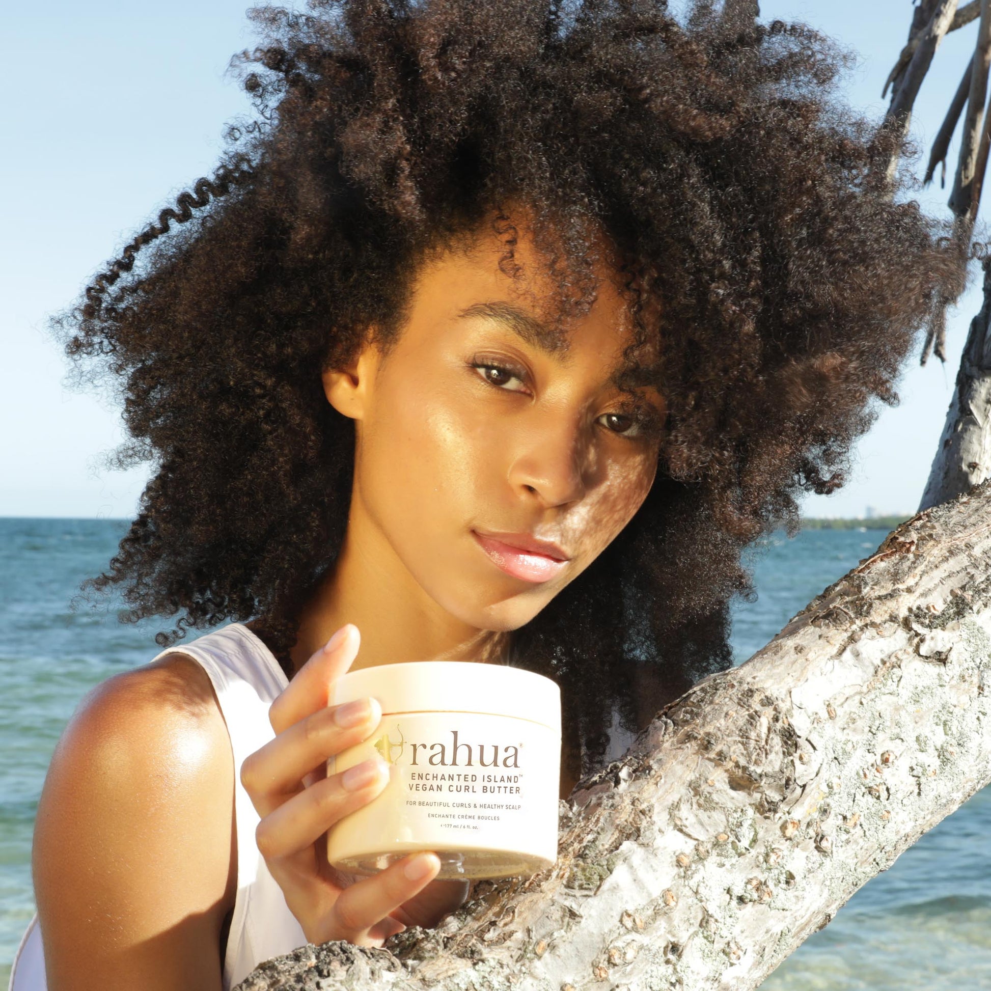 Model with curly hair holding product