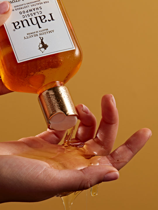 Bottle of Rahua Classic Shampoo poured onto a hand with a yellow background|variant:93-oz