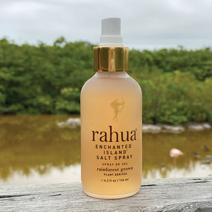 woman holding rahua enchanted island salt spray with green leaves in the background