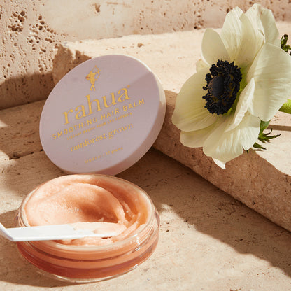 Smooth Creamy texture of rahua hair balm kept with a white flower and marble block